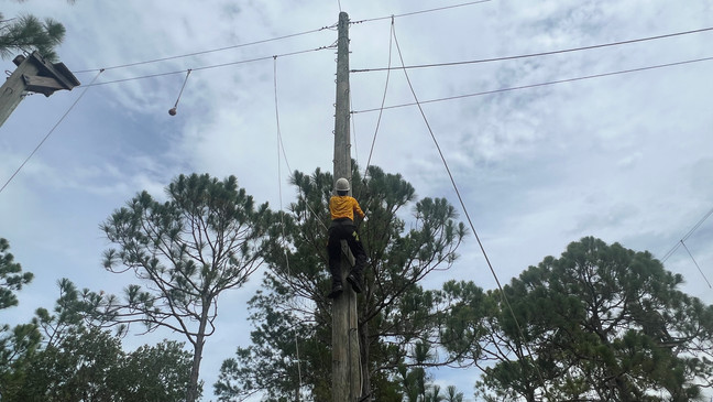 Ali 'Twitch' Carver climbing up to a ropes course high above the ground. (WPEC)